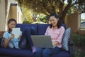 Mother and daughter using digital tablet and laptop while relaxing on couch Royalty Free Stock Photo