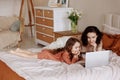 Mother and daughter using laptop on bed in holiday at home. Royalty Free Stock Photo