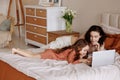 Mother and daughter using laptop on bed in holiday at home. Royalty Free Stock Photo