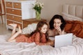 Mother and daughter using laptop on bed in holiday at home. Royalty Free Stock Photo