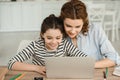 Mother and daughter using laptop together while doing schoolwork at home Royalty Free Stock Photo