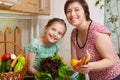 Mother and daughter with vegetables and fresh fruits in kitchen interior. Parent and child. Healthy food concept Royalty Free Stock Photo