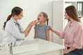 Mother and daughter visiting pediatrician. Doctor examining patient`s throat in hospital Royalty Free Stock Photo