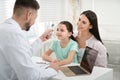 Mother with daughter visiting pediatrician in hospital. Doctor measuring girl`s temperature Royalty Free Stock Photo