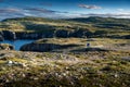 Mother and daughter walk across mossy tundra along the Klondike trail near the famous Chimney Rock in Newfoundland Canada