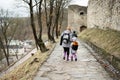 Mother with daughter walk down wet path to an ancient medieval fortress in rain. Terebovlia castle, Ukraine