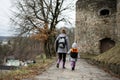 Mother with daughter walk down wet path to an ancient medieval fortress in rain. Terebovlia castle, Ukraine