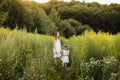 Mother with daughter walking along a country road, background summer meadow sunset, back view Royalty Free Stock Photo