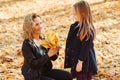 Mother and daughter walking in autumn park. Mom and child playing with autumn leaves Royalty Free Stock Photo