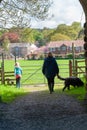 Mother and daughter walking a dog along a country track approaching a gate and style Royalty Free Stock Photo