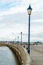 Mother and daughter walking dog along old English wooden jetty lined with street lamps Royalty Free Stock Photo