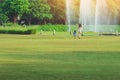 Mother and daughter walking through green garden with fountain in background.Mom and daughter walk together in park.Happy family Royalty Free Stock Photo