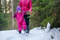 Mother and daughter walking a snowy forest.