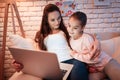 Mother and daughter watching movies on laptop under lampshade at night at home. Royalty Free Stock Photo