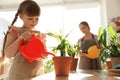 Mother and daughter watering home plants at wooden table