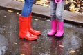 Mother and daughter wearing rubber boots standing in puddle on rainy day, focus of legs. Royalty Free Stock Photo