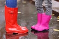 Mother and daughter wearing rubber boots standing in puddle on rainy day, focus of legs Royalty Free Stock Photo