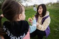 Mother and daughter weave a wreath of flowers in spring meadow