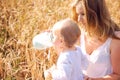 Mother and daughter in wheat field. Happy Family outdoors. healthy child with mother on picnic with bread and milk in golden