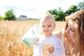 Mother and daughter in wheat field. Happy Family outdoors. healthy child with mother on picnic with bread and milk in golden