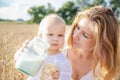 Mother and daughter in wheat field. Happy Family outdoors. healthy child with mother on picnic with bread and milk in golden