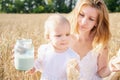 Mother and daughter in wheat field. Happy Family outdoors. healthy child with mother on picnic with bread and milk in golden