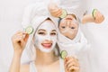 Mother and daughter in white shirts and white towels on their heads in a home bathroom, doing spa procedures with mud Royalty Free Stock Photo