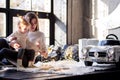 Mother and daughter in white sweaters sit on the floor near a large window and examine the New Year`s garland Royalty Free Stock Photo