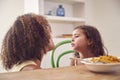 Mother With Daughter Who Is Fussy Eater Sitting Around Table At Home For Family Meal