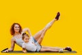 Mother and daughter working out, raising leg over yellow background
