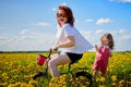 Mother and daughter wtht a bicycle in a field with yellow dandelions. Family walks in the spring in nature Royalty Free Stock Photo