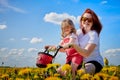 Mother and daughter wtht a bicycle in a field with yellow dandelions. Family walks in the spring in nature Royalty Free Stock Photo