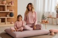 Mother-Daughter Yoga Bliss. Happy Woman and Small Child in Serene Pink Ambience at Home