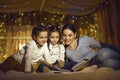 Mother with daughters children reading book spending time in home tent