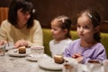 Mother with daughters eating desserts together at cozy cafe and having fun Royalty Free Stock Photo