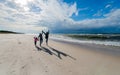 Mother with daughters jumping on the seaside beach on a sunny windy day - a family walk by the sea Royalty Free Stock Photo