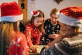 Mother with daughters kids playing together in table board game, wearing Christmas hats. Cozy pre Christmas evening time moment.