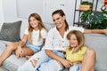 Mother and daughters smiling confident sitting on sofa at home