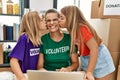 Mother and daughters wearing volunteer uniform kissing and working at charity center