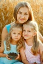 Mother and daughters in a wheat field. A happy family in the fresh air on a picnic outside the city on a sunny summer day