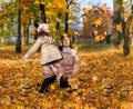 Mother and daugter playing with fallen yellow leaves. Portrait of a happy people in an autumn park