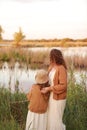 Mother day. Back view of young mom with little girl are standing near lake, pond on summer day. Family enjoying life Royalty Free Stock Photo