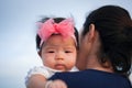 Mother day bonding concept with newborn baby nursing. Mother is holding newborn baby with flower pink headband with blue sky. Focu Royalty Free Stock Photo