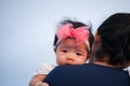 Mother day bonding concept with newborn baby nursing. Mother is holding newborn baby with flower pink headband with blue sky. Focu Royalty Free Stock Photo