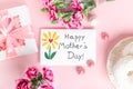 Mother day greeting card on pink background. Breakfast, carnation gift and a postcard made by the child for mom.