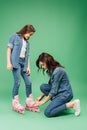 Mother in denim putting roller blades on daughter Royalty Free Stock Photo