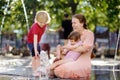 Mother with disabled girl and boy having fun on fountain at sunny summer park. Child cerebral palsy. Family with disabled kid Royalty Free Stock Photo