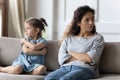 Mother disobedient daughter sit apart on sofa feeling discontent