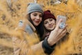 Mother and doughter teenager are walking on the street in warm autumn clothes