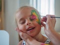 Mother drawing butterflies on face her baby daughter